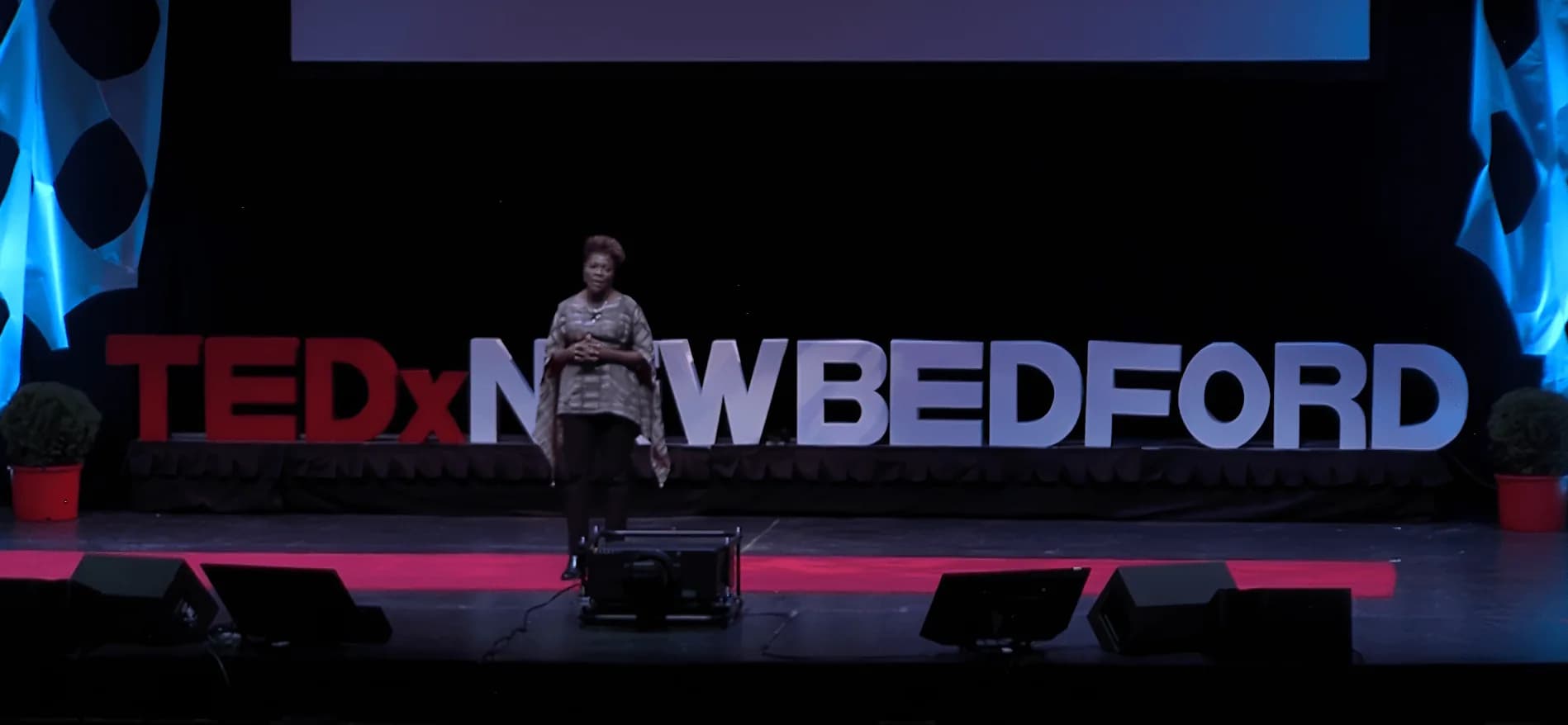 Dr. TLC on the TEDx stage speaking to a full auditorium